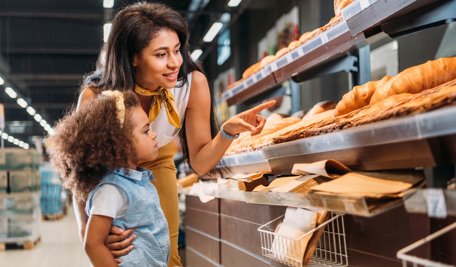 Mother and daughter looking at bread in bakery