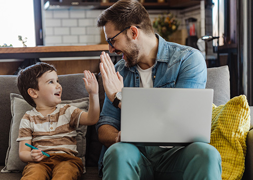 Father and son using laptop in living room